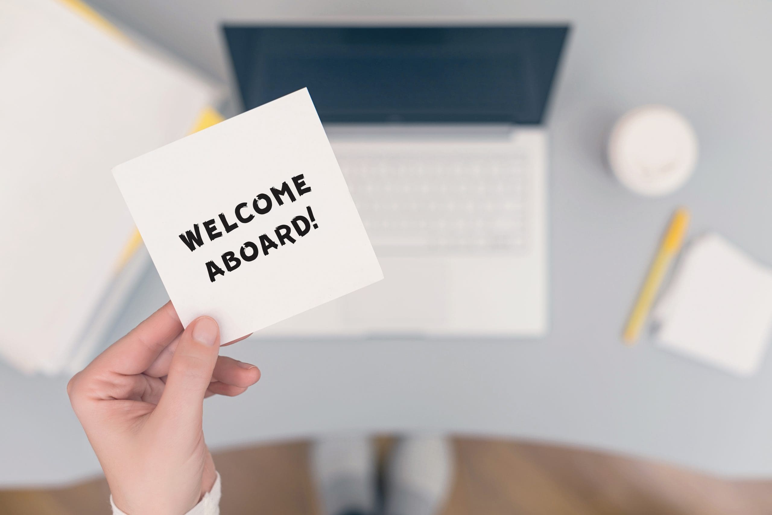 Woman clerk sitting holding note paper sticker with welcome aboard phrase. Business concept. Woman clerk sitting holding note paper sticker with welcome aboard phrase. Business concept.