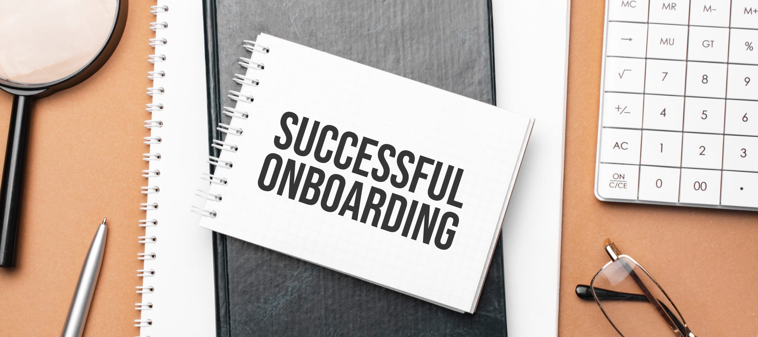 successful onboarding on notepad and various business papers on brown background. Brown glasses and magnifier with notepad. successful onboarding on notepad and various business papers on brown background. Brown glasses and magnifier with notepad.